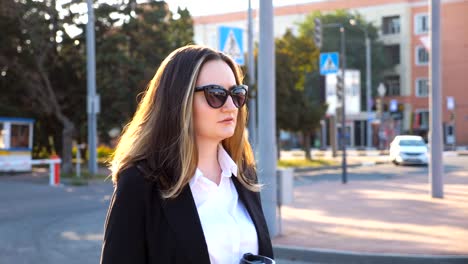 Perfil-de-empresaria-joven-caminando-por-la-calle-urbanita-al-atardecer.-Mujer-de-negocios-va-a-funcionar.-Chica-confía-en-estar-en-su-camino-a-la-oficina.-El-sol-de-la-llamarada-en-el-fondo.-Lenta-de-cerca