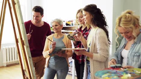 group-of-artists-discussing-painting-at-art-school