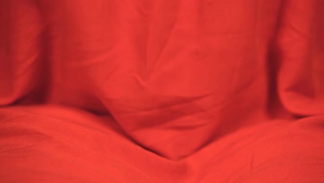 Female-buddhist-in-colorful-red-robe-prepares-for-meditation,-hands-crossed