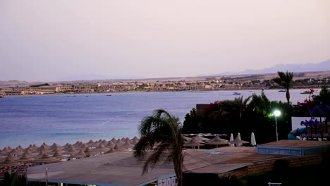 Egyptian-resort.-One-of-many-quiet-coves-of-the-Red-Sea,-at-sunset,-at-dusk.-against-the-background-of-the-outlines-of-buildings,-palm-trees,-mountains