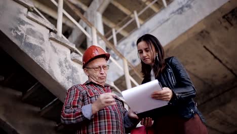 Frau-Ingenieur-im-Gespräch-mit-einem-Vorarbeiter-auf-der-Baustelle,-organisatorische-Probleme-zu-lösen.