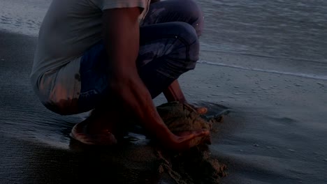 black-man-bowed-on-the-bath-tub-touching-the-sand.-Mother-earth,-nature,-contact