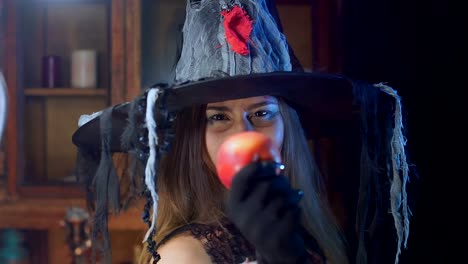 Halloween-witch-in-a-hat-is-holding-a-poisonous-apple.