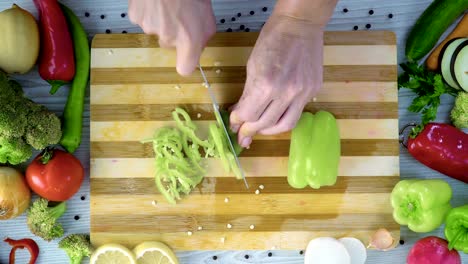 Man-is-cutting-vegetables-in-the-kitchen,-slicing-fresh-green-bell-pepper