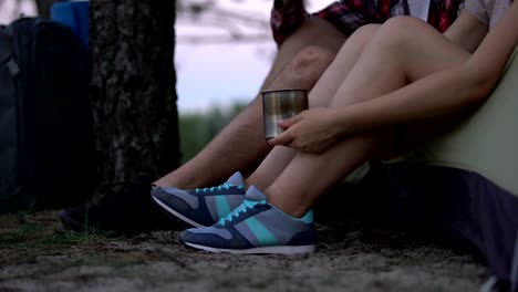 Excursionistas-en-los-zapatos-de-deporte-sentado-en-la-tienda,-beber-té,-descansando-después-de-día