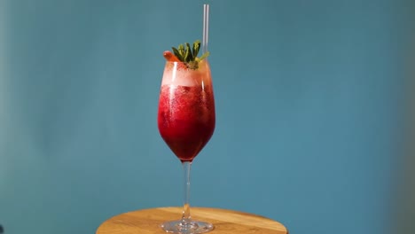 Gira-cocktail-sobre-fondo-azul,-coctel-rojo-sobre-fondo-azul,-cóctel-alcohólico-sobre-fondo-azul