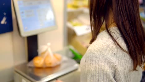 Young-woman-in-the-vegetable-department-of-a-supermarket-weighs-tangerines