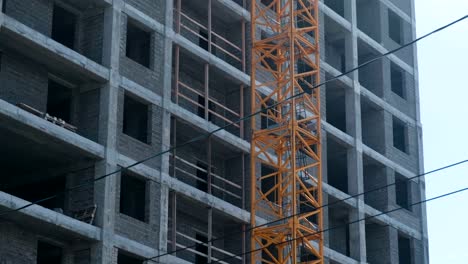 Multi-storey-under-construction-building-and-construction-crane-on-the-background-of-clear-sky.