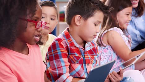 Grundschule-Kinder-mit-Tablet-Computern-in-der-Klasse-zu-sprechen
