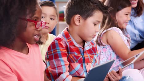 Elementary-school-kids-with-tablet-computers-talk-in-class