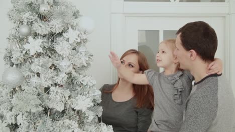 The-family-is-standing-near-the-Christmas-tree,-laughing-talking-and-touching-toys-while-waiting-for-Christmas