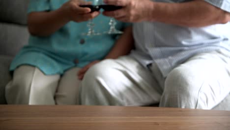 Senior-couple-sitting-and-talking-with-red-wine-glass-on-table-in-living-room.