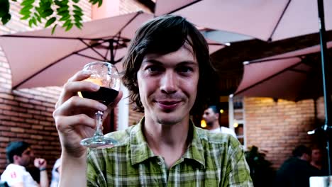 Man-on-a-date-raises-a-glass-of-wine-and-clink-glasses.-Guy-in-love-smiles-in-a-restaurant-at-a-romantic-dinner