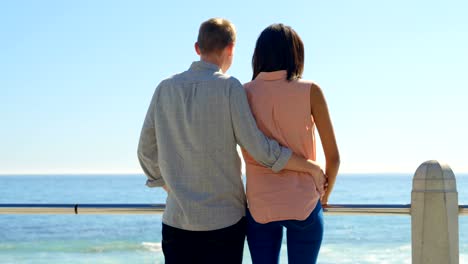 Rear-view-of-couple-talking-while-looking-at-the-calm-sea-4k