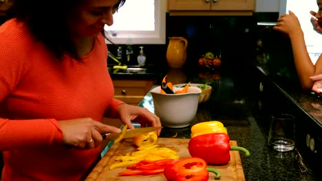 Kids-using-laptop-and-digital-tablet-while-mother-cutting-vegetables-4k