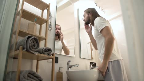 Hombre-en-el-baño-mirando-en-el-espejo-y-tocarse-la-cara