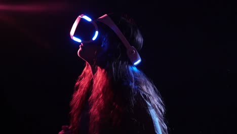 Young-woman-in-VR-headset-standing-in-dark-space