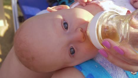 Baby-liegt-auf-dem-Schoß-der-Mütter-und-trinkt-aus-der-Flasche