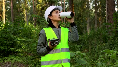 Woman-holding-Drone-quadcopter-and-drinking-coffee-before-forest-inspection