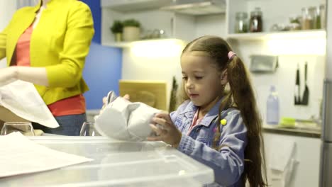 Woman-unpacks-things,-her-little-daughter-helps-her