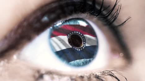 Woman-blue-eye-in-close-up-with-the-flag-of-Missouri-state-in-iris,-united-states-of-america-with-wind-motion.-video-concept