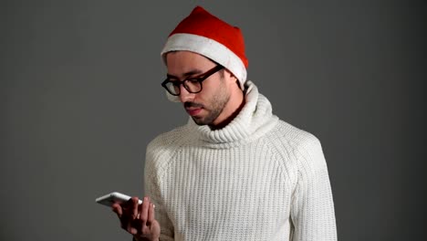 Serious-brutal-man-in-glasses-and-a-red-cap-of-Santa-Claus-calling-by-phone-and-is-angry-that-no-dials