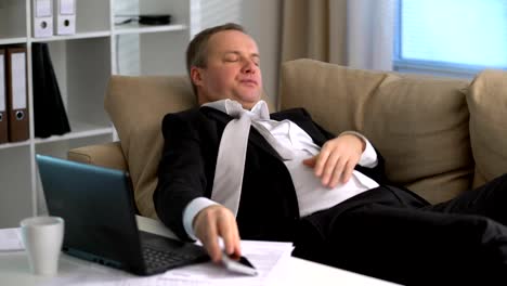 Tired-businessman-is-sleeping-on-the-sofa-at-the-office