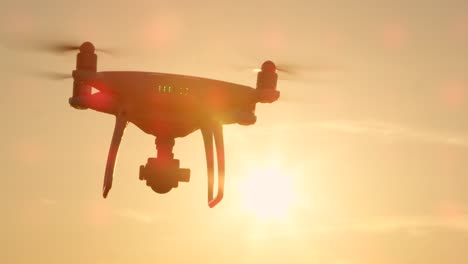 SLOW-MOTION-CLOSE-UP-SILHOUETTE:-Drone-flying-over-the-sun-on-golden-sunset-sky