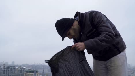 Obdachlose-sucht-etwas-in-den-Müllsack-im-städtischen-Hintergrund