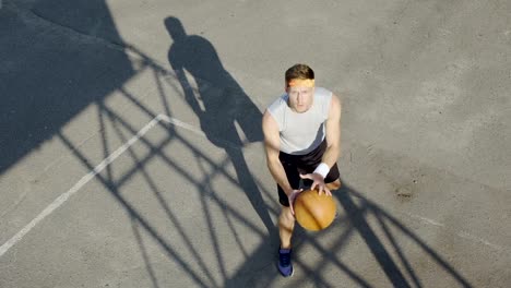 Junger-Mann-allein,-Basketball-spielen,-einen-Ball-dribbeln-und-Freiwürfe-üben