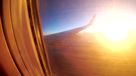 Blick-aus-dem-Fenster-eines-Passagier-Flugzeug-während-des-Sonnenuntergangs-auf-eine-Landschaft-und-Horizont