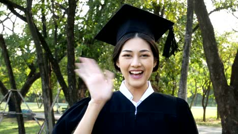 Jóvenes-estudiantes-mujer-Asia-usando-graduación-sombrero-y-vestido,-fondo-del-jardín,-mujer-con-el-concepto-de-graduación.