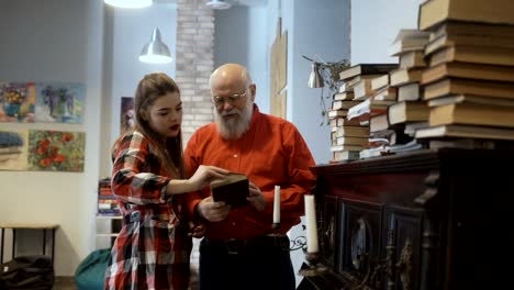 Gray-haired-grandfather-and-granddaughter-read-interesting-book-together