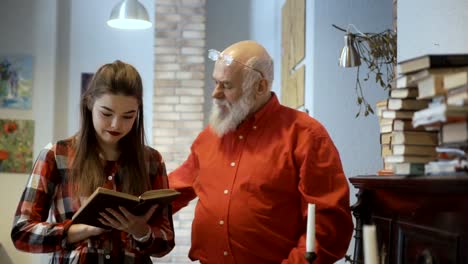 Young-pretty-girl-reads-interesting-book-together-with-grandfather