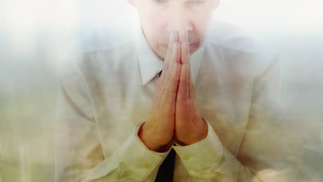 Reflection-of-a-businessman-praying-against-a-window