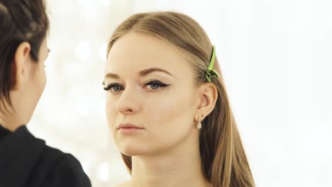 Profesional-maquilladora-con-cosméticos-cepillo-para-presentadora-de-TV-maquillaje-cara-mujer.-Cerca-de-visagist-haciendo-cara-de-maquillaje-para-la-mujer-actriz-o-modelo-de-moda