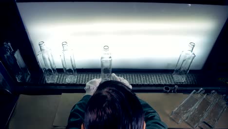 A-female-worker-checks-bottles-on-a-conveyor.