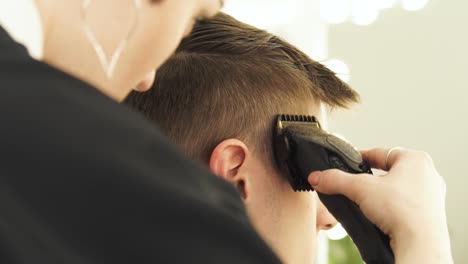 Friseur-mit-elektrischen-Rasierapparat-für-männliche-Haarschnitt.-Haarschneider-für-männliche-Frisur-hautnah.-Professioneller-Friseur-Haare-schneiden-mit-clipper