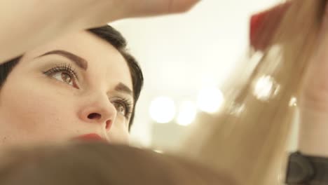 Face-woman-hairdresser-cutting-long-hair-with-hairdressing-scissors-in-beauty-salon.-Close-up-haircutter-making-female-haircut-with-scissors-in-hairdressing-salon