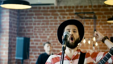 Emotional-bearded-guitarist-singing-into-microphone