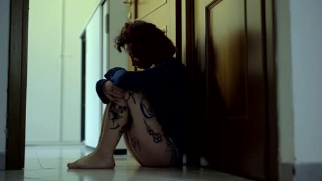 Domestic-Violence:Depressed-and-scared-woman-sitting-in-ground-in-the-dark