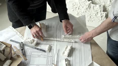 Hands-of-two-male-designers-choosing-molding-samples