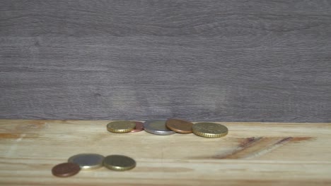 Business-concept---man-hand-collect-euro-coins-on-the-wooden-table.