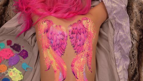 Woman-lying-on-the-floor-with-painted-wings-on-her-back