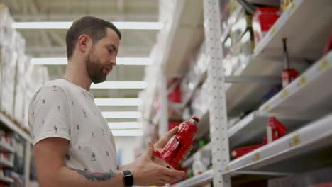 Driver-man-is-holding-a-pneumatic-lift-jack-in-hand-in-a-shop-for-automobilists