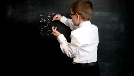 Young-boy-solving-maths-expression-on-a-blackboard.-Creative-concept-of-back-to-school-and-study.-Pre-school