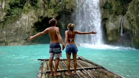 Young-couple-being-affectionate-at-beautiful-tropical-waterfall-in-the-Philippines-enjoying-vacations-and-freedom.-People-travel-love-concept