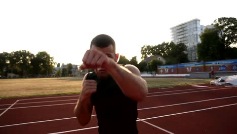 Handhelded-hautnah-Aufnahmen-von-einer-wütenden-männlicher-Boxer-training-auf-dem-Outdoor-Stadion.-Porträt-eines-Mannes-mit-unsichtbaren-Gegner-Boxen,-Stanzen