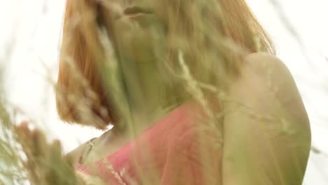 Calm-red-haired-woman-touches-wheat-rye-crops-outdoors,-serious-female-face-slow