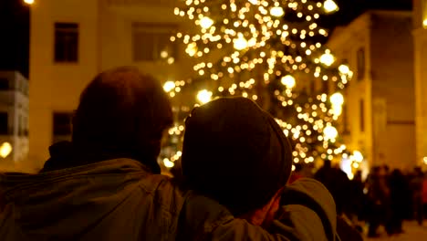 christmas-holiday:-mature-couple-looking-at-christmas-tree-in-town-square